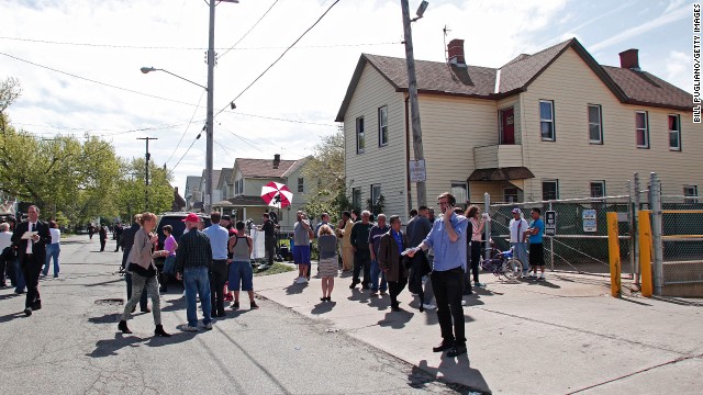 Bystanders and media gather on May 7 along Seymour Avenue in Cleveland near the house where the three women were held captive.