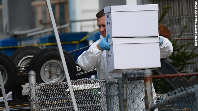 An FBI forensics team member removes evidence from the house.