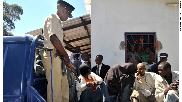 Philip Mubiana (covering his face) and James Mwape (left) arrive at the Kapiri magistrate court on May 8, 2013 in Lusaka. 