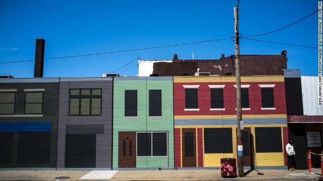 A man stands on Clark Avenue in front of painted buildings. 