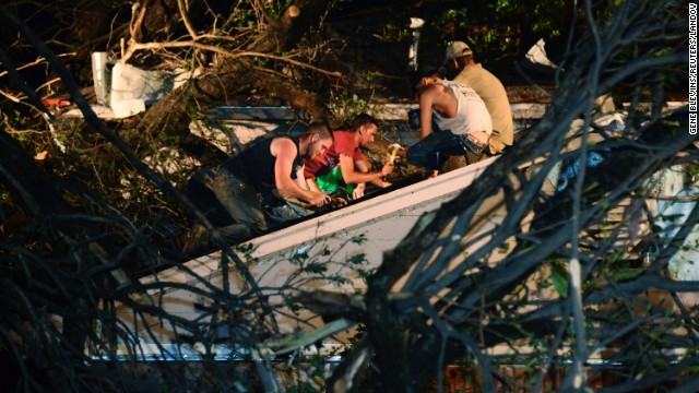 Residents repair the roof of a neighbor's damaged house after a tree fell on it in Shawnee, Oklahoma, on May 19.