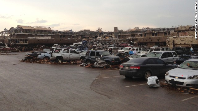 A shopping center parking lot is covered with debris and damaged cars on May 20.