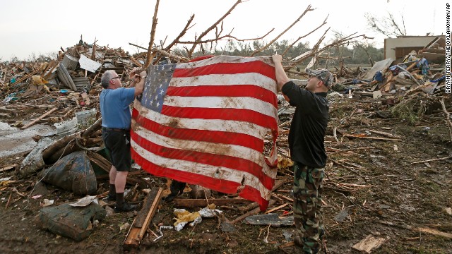 Men tie an American flag on debris in a neighborhood off Telephone Road in Moore on May 20.