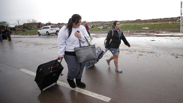 Bonnie Lolofie, left, and Ashley Do carry belongings from their apartment, which has no power, on May 21.