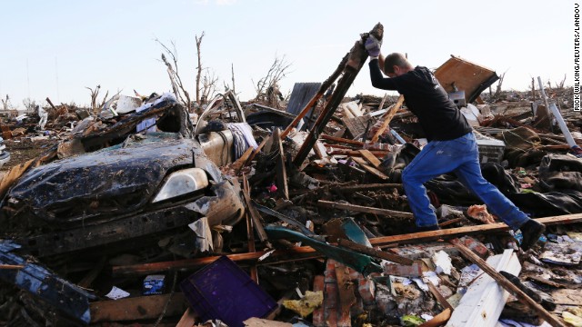 Jon Booth moves a piece of debris from his mother's destroyed home across the street from Plaza Towers Elementary School on May 22.