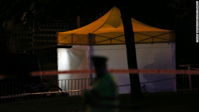 A police officer guards a tent that's been set up at the crime scene as investigations continue late May 22.