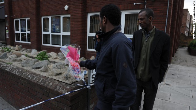 Men place flowers near the scene on John Wilson Street.