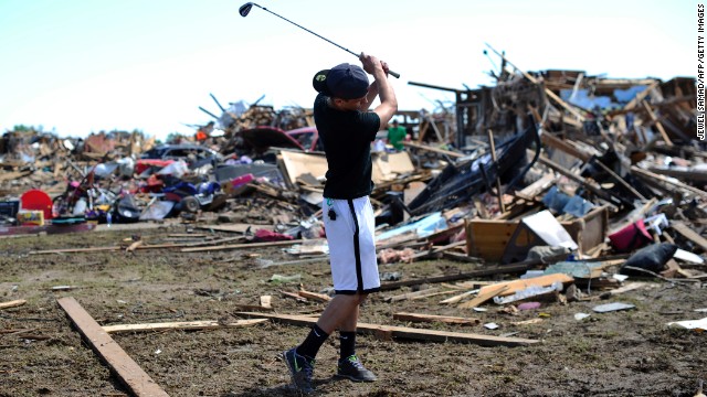 Michael Pritz swings a golf club while taking a break from helping his friend to salvage belongings on May 22.