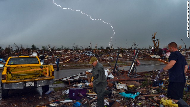 Lightning strikes during a thunderstorm as people search for items that can be saved from their devastated home on May 23.