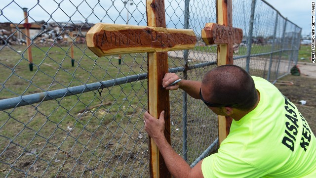 A volunteer signs a cross on May 25 at a makeshift memorial outside of the destroyed Plaza Towers Elementary School where seven children were killed in Monday's tornado in Moore.