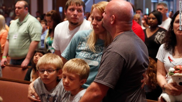 Tornado victims Christa and Russell Smith hug their children, Evan and Justin Smith, as the service takes place. 