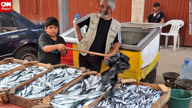 A child waves flies away from a fish seller's stall in a <a href='http://ireport.cnn.com/docs/DOC-811843'>Tripoli market</a>.