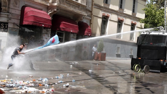 Protestors brace themselves as they are fired upon with a water canon by Turkish police forces.