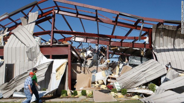 Two men walk by a damaged OKC-West Livestock Market building near El Reno on June 1. 