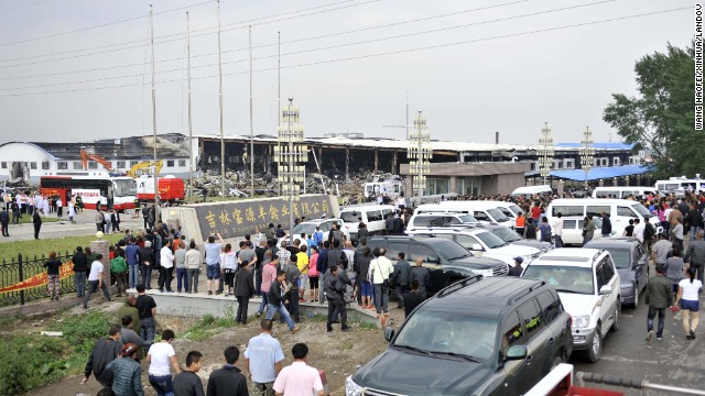 People gather at the site of the fire, which an official says was started by an explosion.