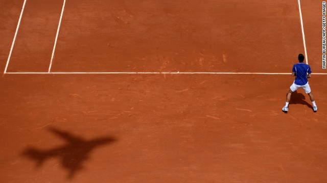 The shadow of a plane-shaped camera appears on the court as Djokovic waits for a serve from Kohlschreiber on June 3.