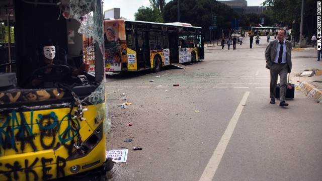 A man walks past damaged buses near Taksim Square on Thursday, June 6, in Istanbul, Turkey.