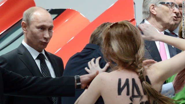 A topless protester shouts at Putin and German Chancellor Angela Merkel, center, during their visit to the Hanover Industrial Fair in central Germany on April 8. Human rights groups say civil liberties and democratic freedoms have suffered during Putin's rule.