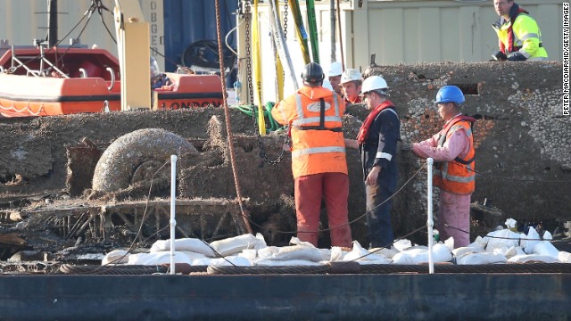 Salvage workers inspect the bomber after it was lifted from the water.