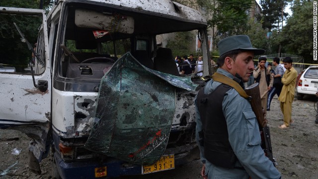 An Afghan policeman stands guard in front of a badly damaged bus at the site of a suicide attack in Kabul on June 11, 2013. More than 1,000 Afghan civilians died in violent attacks in the first half of 2013, according to the U.N.