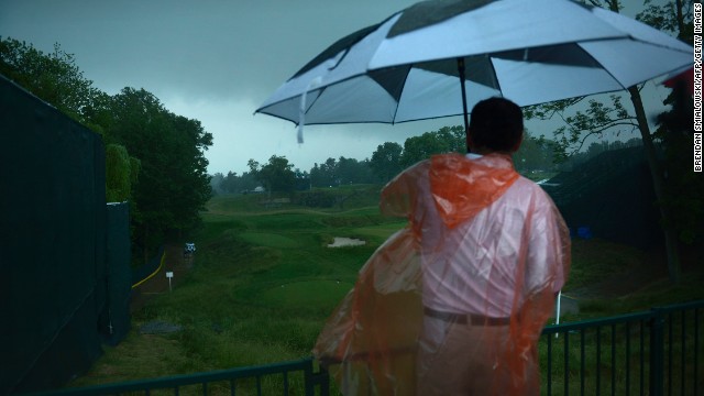 A man looks out over the 18th hole after play was suspended during a storm on June 13.