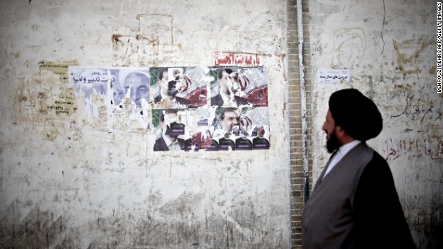 An Iranian clergyman walks past campaign posters on June 9 in Qom, south of the capital city of Tehran.