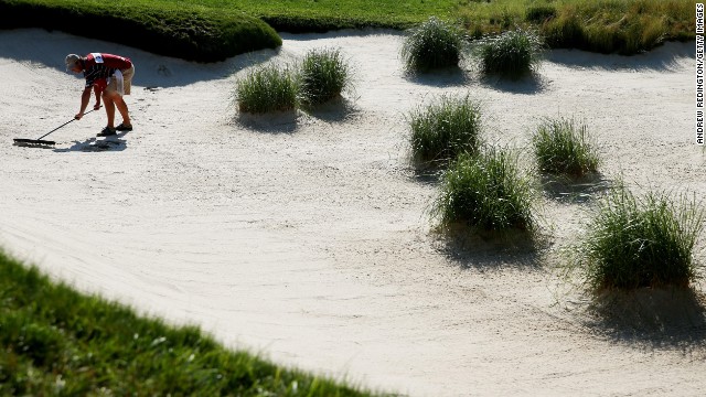 A caddie rakes a bunker at the 10th hole on June 15.