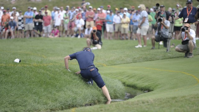 Luke Donald climbs up a bank after hitting out of a water hazard at the 4th hole on June 16.