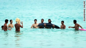 Tourists pose with a dying dolphin.