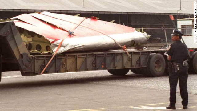 A police officer stands guard as part of the plane is transported from a dock in Brooklyn, New York, on July 19, 1996.