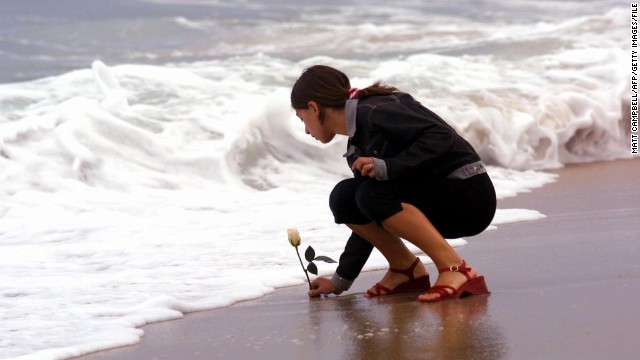 Antonella Naglieri, whose relatives Giuseppe Mercurio and Anna D'Alessandro were killed in the crash, places a rose in the surf after a memorial service at Smith Point Park in Shirley, New York, on July 17, 2001.