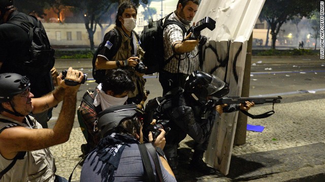 Photographers wait for a riot police officer to fire rubber bullets on June 20 in Rio de Janeiro.