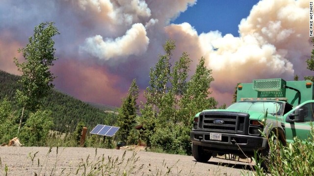 The West Fork Fire Complex burns 15 miles north of Pagosa Springs, on June 20, as a fire crew truck is parked nearby.