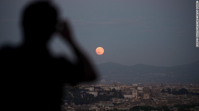 Onlookers view the full moon over the city of Rome on June 23.