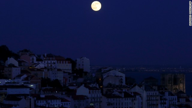 The full moon rises over Lisbon, Portugal, on June 23.