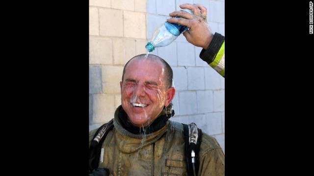 A Salt Lake City fireman pours water over the head of fireman Cary Turner after battling a house fire on Wednesday, June 26. Temperatures in Utah are approaching record highs.