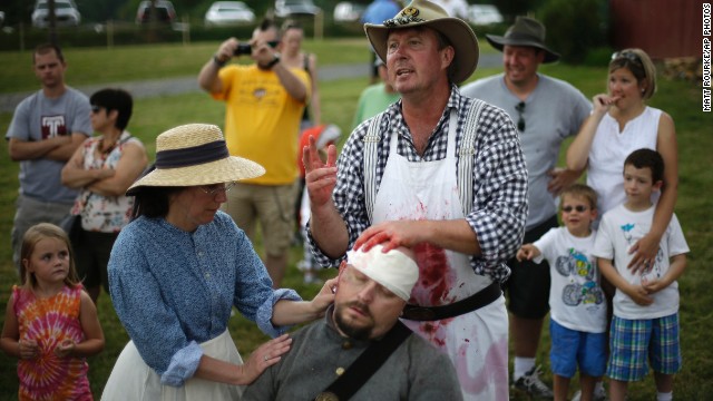 Spectators watch as reenactors portray medical treatment at a Confederate field hospital at the Daniel Lady Farm in Gettysburg.