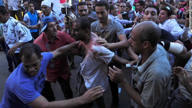 Egyptians help a wounded man following clashes between Morsy's supporters and opponents in Alexandria on June 28.