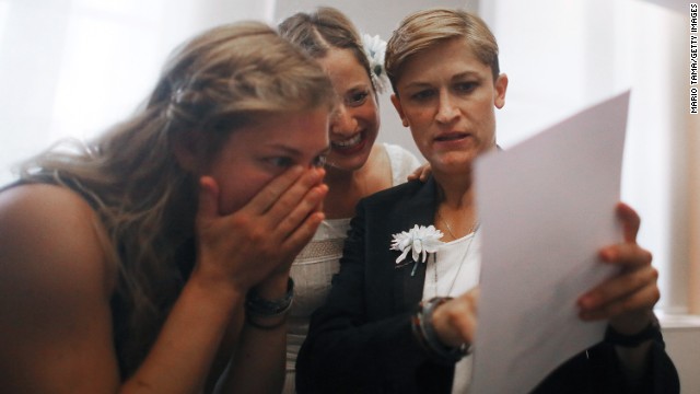 Stefanie Berks, center, and Daisy Boyd, right, view their marriage certificate with a friend after their ceremony in the east chapel at the Manhattan Marriage Bureau on June 28.