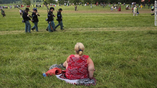 A spectator watches the event on June 30 from a seat on the grass.