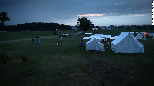 Reenactors take shelter from an evening rain storm in tents on June 29. 