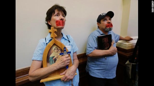 Anti-abortion demonstrators tape the word "life" over their mouths as they stand in the rotunda of the Texas capitol on July 1.