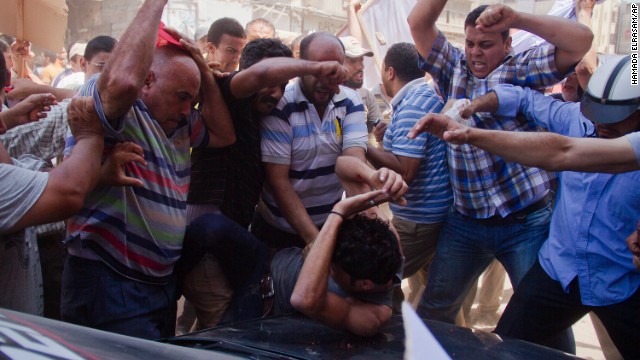 An opposition protester is beaten by pro-Morsy demonstrators during clashes in Damietta on July 3.
