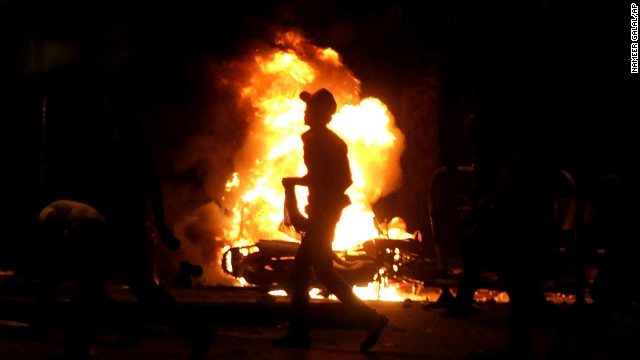 A protester runs past a fire raging during clashes in Giza, Egypt, early on July 3.