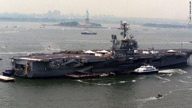 The aircraft carrier USS John F. Kennedy is anchored in New York Harbor near the Statue of Liberty in preparation to carry President Bill Clinton and first lady Hillary Clinton during Independence Day festivities in 2000.