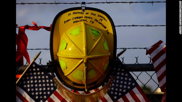 A firefighter's helmet from a Texas volunteer department hangs on a fence at a makeshift memorial to the fallen Granite Mountain Hotshots in Prescott on July 4.