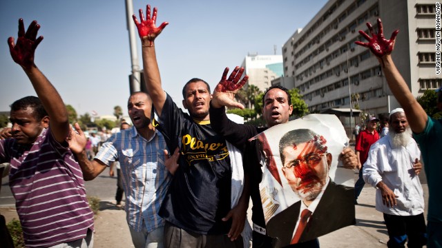 Morsy supporters hold up their bloodstained hands after Egypt's armed forces opened fire on rally in front of the Republican Guard headquarters in Cairo on July 5.