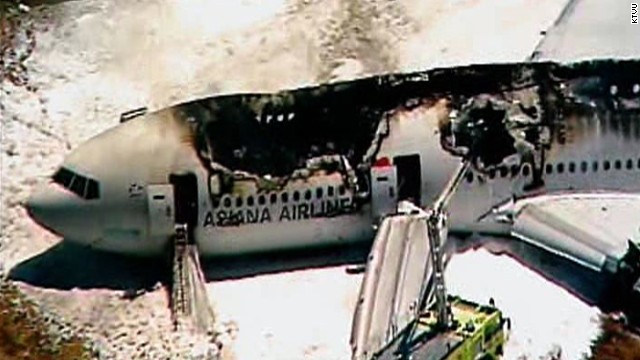 Firefighters attempt to put out the flames and evacuation slides can be seen protruding from the plane on July 6.