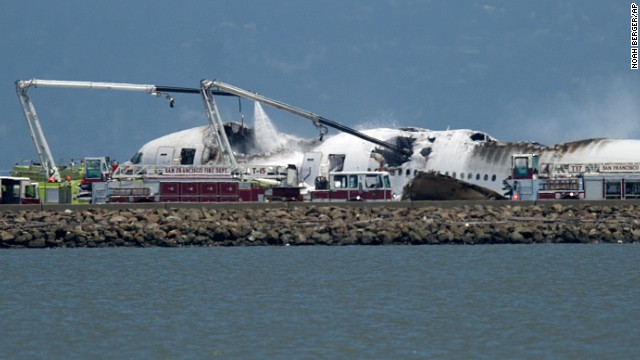 A fire truck sprays water on the charred plane on July 6.
