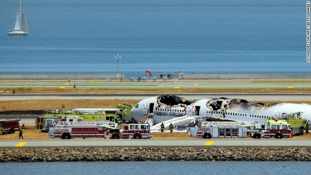The burned-out plane sits surrounded by emergency vehicles on July 6.